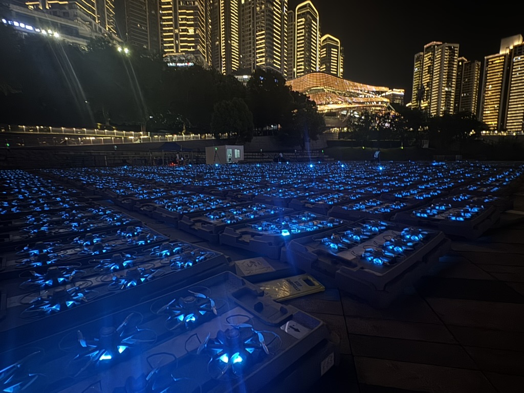 Thousands of illuminated drones prepared beside Chongqing's nighttime skyline.