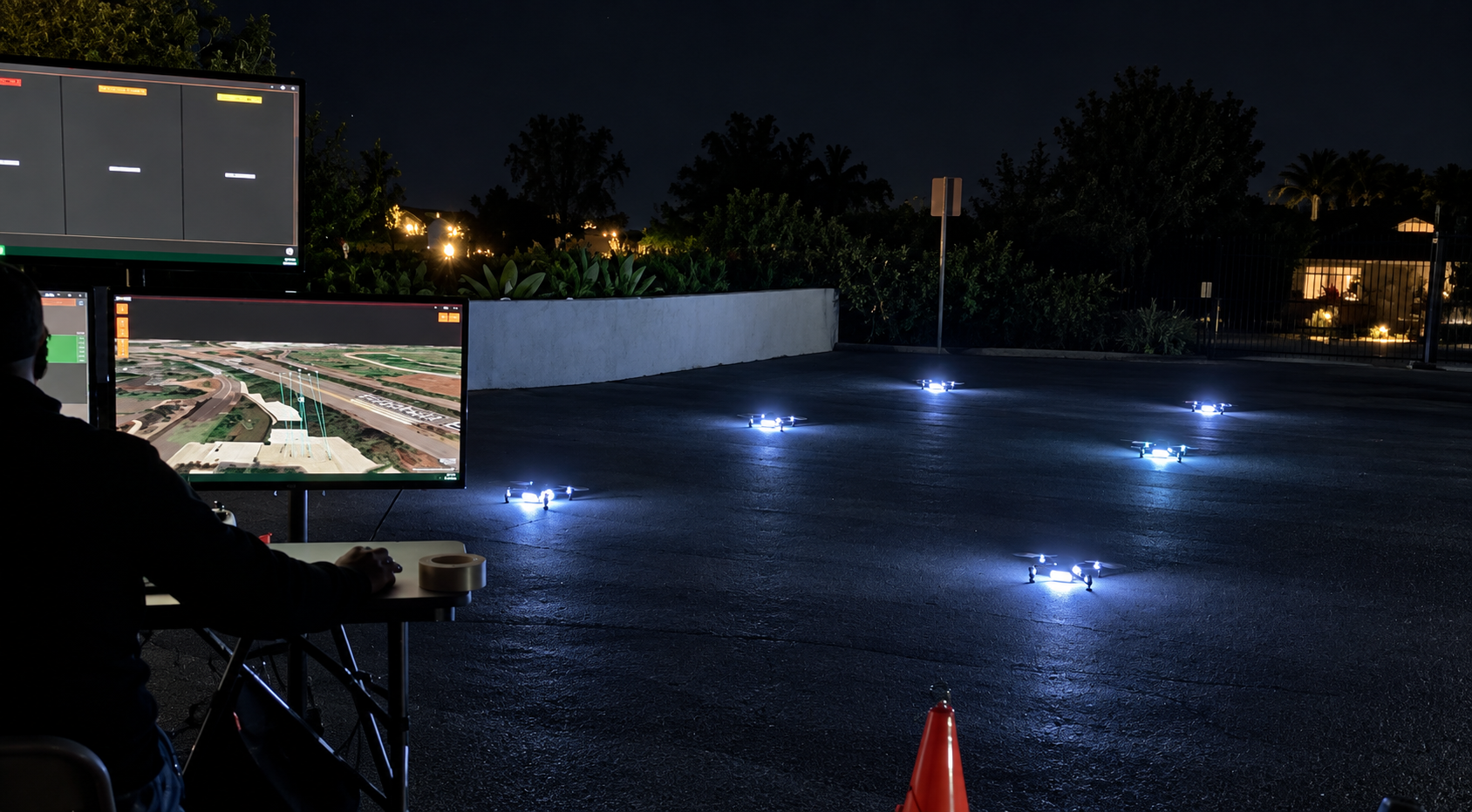 Six illuminated drones prepared beside the ground-control station at night.